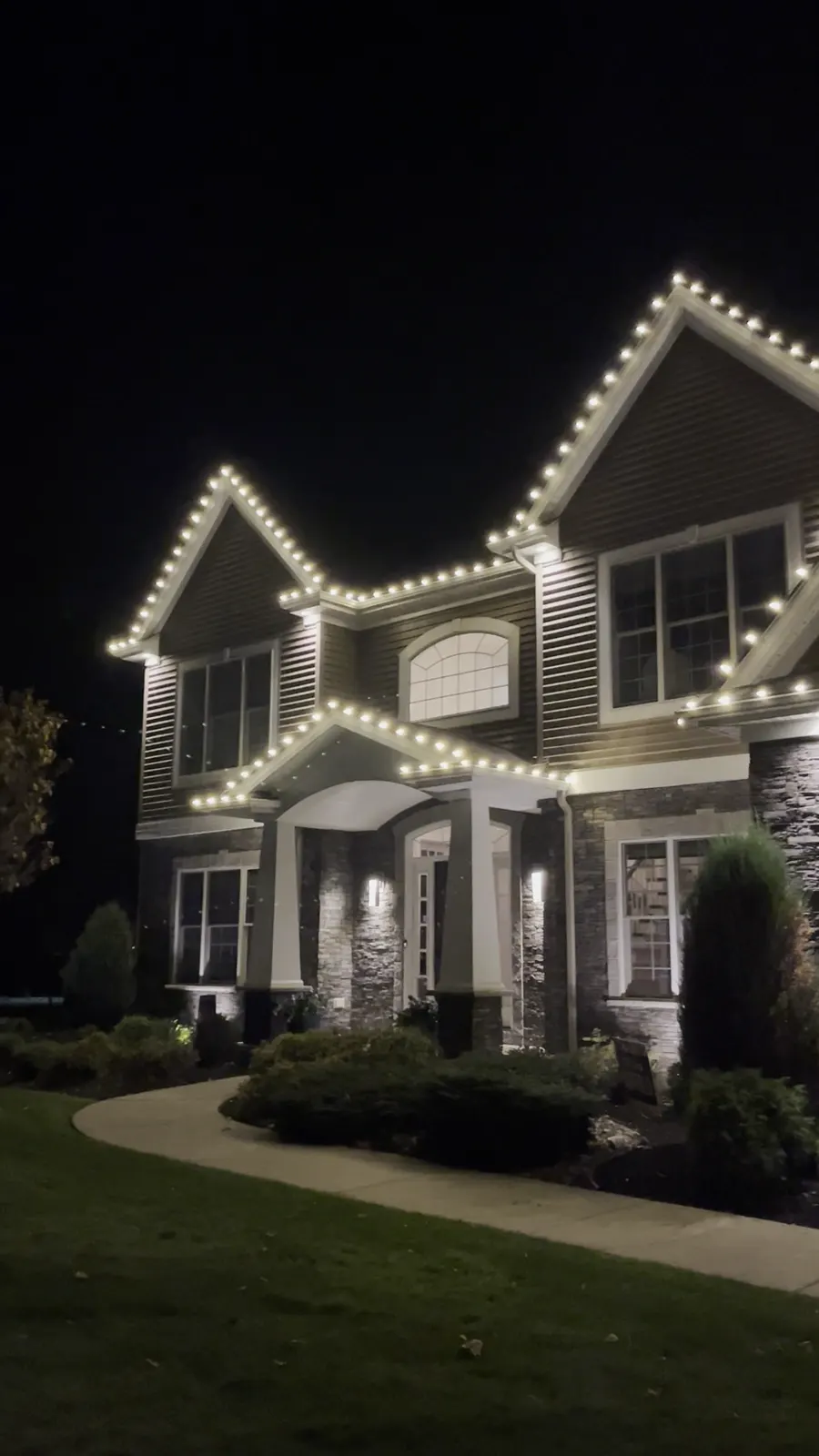 Clarence stone-front home with white bulbs on every gable