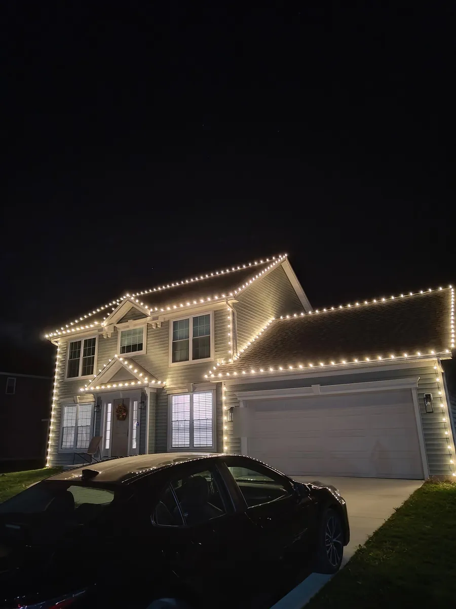 Two-story home in West Seneca outlined in warm white bulbs from roof peaks to corners